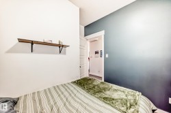 Interior room featuring a wood-finish floating shelf with black metal brackets, a white paneled door frame, a light gray wall, and an accent wall with an ombre blue-to-white finish - 