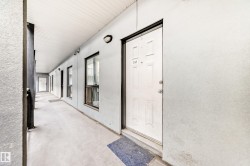 Exterior entry featuring a paneled door with numeric signage, an overhead light fixture, and a window - 