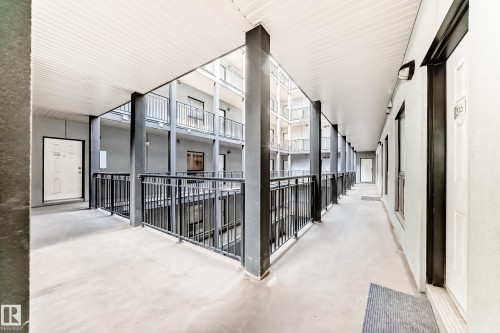 Multi-story building exterior featuring a courtyard-style design, covered walkways, black metal railings, and individual unit entry doors - 316 10518 113 Street, Edmonton, AB - Outdoor