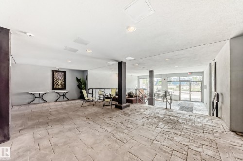 Spacious common area featuring textured concrete flooring, recessed lighting, and a prominent dark structural column - 316 10518 113 Street, Edmonton, AB - Indoor