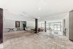 Spacious common area featuring textured concrete flooring, recessed lighting, and a prominent dark structural column - 