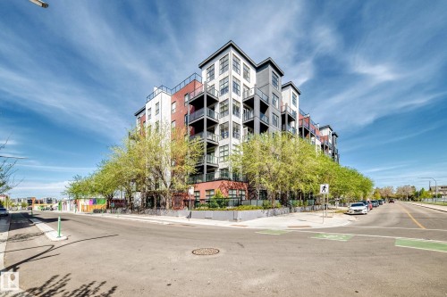 Contemporary multi-story building featuring a multi-toned facade, multiple balconies, mature trees, and a corner street presence with pedestrian crossings - 316 10518 113 Street, Edmonton, AB - Outdoor With Balcony With Facade