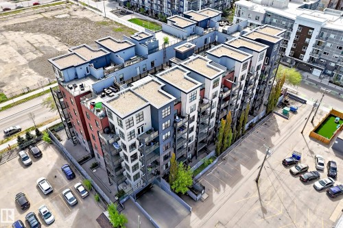 Contemporary multi-story building featuring a facade with varied colors and materials, including red paneling, dark gray siding, and light-colored accents - 316 10518 113 Street, Edmonton, AB - 