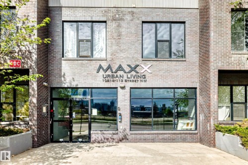 Brick facade building entrance featuring a glass door, large storefront windows, and upper-level windows with black frames - 316 10518 113 Street, Edmonton, AB - Outdoor