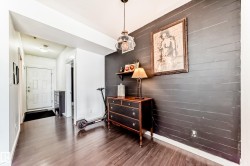 Entryway featuring rich wood-finish flooring, a paneled entry door, and a striking dark accent wall with horizontal paneling - 