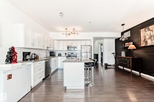 Open-concept kitchen featuring white shaker cabinetry, stainless steel appliances, and a subway tile backsplash - 316 10518 113 Street, Edmonton, AB - Indoor Photo Showing Kitchen