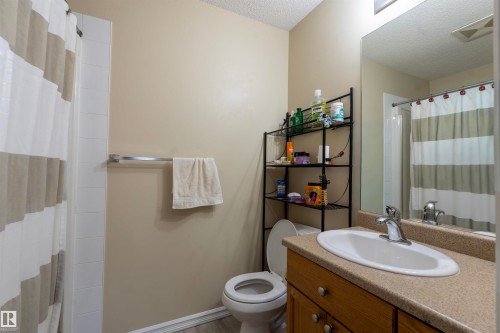 Bathroom featuring a vanity with wood-finish cabinetry, a white basin, and a speckled countertop - 203 4403 23 Street, Edmonton, AB - Indoor Photo Showing Bathroom