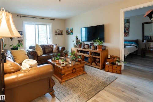 Living area featuring light wood-finish flooring and a glass sliding door - 203 4403 23 Street, Edmonton, AB - Indoor Photo Showing Living Room
