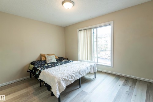 Room featuring wood-finish flooring, a neutral wall color, and a ceiling-mounted light fixture - 203 4403 23 Street, Edmonton, AB - Indoor Photo Showing Bedroom