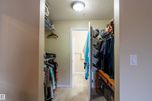 Walk-in closet featuring light wood-finish flooring, built-in wire shelving, and a ceiling-mounted light fixture - 203 4403 23 Street, Edmonton, AB - Indoor