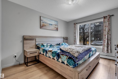 Room featuring large window, wood-finish flooring, light gray walls, and ceiling-mounted light fixture - 128 390 Windermere Road, Edmonton, AB - Indoor Photo Showing Bedroom