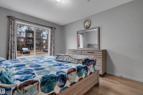 Spacious interior featuring wood-finish flooring and a sliding glass door providing natural illumination - 128 390 Windermere Road, Edmonton, AB - Indoor Photo Showing Bedroom