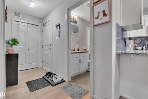 Entryway featuring light wood-finish flooring and a white two-panel closet door - 128 390 Windermere Road, Edmonton, AB - Indoor Photo Showing Other Room
