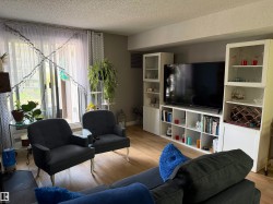Living area featuring wood-finish flooring, a full-wall built-in media center, and expansive glass doors opening to the outdoors - 