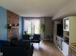 Living area featuring a brick-clad fireplace with a wood mantle, wood-finish flooring, and white built-in cabinetry - 