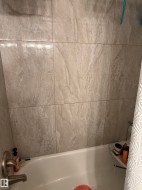 Bathtub with brushed nickel fixtures and light-toned tile surround - 