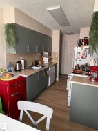 Galley kitchen featuring wood-finish flooring, grey cabinetry with brushed nickel hardware, and light-toned countertops - 