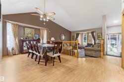 Vaulted ceiling dining area featuring wood-finish flooring, a decorative chandelier fan, and a built-in display cabinet - 
