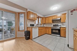 Kitchen featuring wood cabinetry, stainless steel range with overhead microwave, and light-toned tile flooring - 