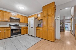 Kitchen featuring extensive wood cabinetry, tile flooring, stainless steel range with overhead hood, and a decorative tile backsplash - 