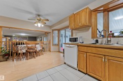 Kitchen and dining area featuring wood-finish cabinetry, a stainless steel sink, and white tile flooring - 