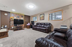 Living area featuring a brick accent wall, neutral carpeting, and a ceiling-mounted light fixture - 