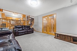 Carpeted living area featuring light gray walls, a built-in entertainment console, and double French doors with glass panels - 