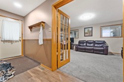Living area featuring light grey carpeting, recessed lighting, and windows with wood trim - 