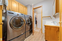 Laundry area featuring wood-finish flooring and upper cabinetry - 
