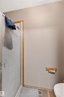 Shower enclosure with a framed glass door, textured ceiling, and wood-finish flooring - 