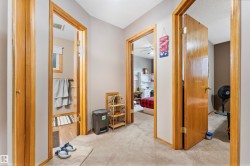 Hallway featuring neutral carpet flooring and light wood-finish doors and trim - 