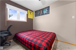 Bedroom featuring a double-pane window with wood trim, neutral tone walls, and carpet flooring - 