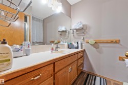 Bathroom vanity featuring a light-toned countertop, integrated sink, and wood cabinetry with multiple drawers and doors - 