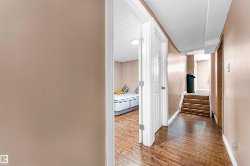 Hallway featuring wood-finish flooring, light tan wall paint, and white trim - 4231 32 Avenue, Edmonton, AB - Indoor Photo Showing Other Room