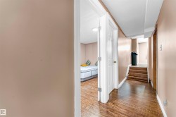 Hallway featuring wood-finish flooring, light tan wall paint, and white trim - 