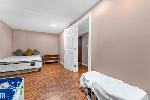 Room featuring wood-finish flooring, neutral wall paint, and a white six-panel interior door with white trim - 4231 32 Avenue, Edmonton, AB - Indoor Photo Showing Bedroom