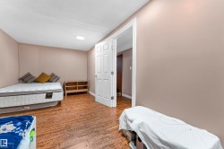 Room featuring wood-finish flooring, neutral wall paint, and a white six-panel interior door with white trim - 