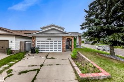 Brick and siding exterior featuring an attached garage with a panel door, a covered entry, and a front yard with a raised planter bed - 