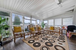 Sunroom featuring a vaulted panel ceiling, numerous windows with blinds, wood-finish flooring, and a ceiling fan - 