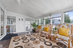 Enclosed sunroom featuring a white slatted ceiling, wood-finish flooring, multiple large windows, and a ceiling fan - 