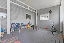 Covered outdoor porch featuring a wood-finish floor, light gray siding, and two exterior wall-mounted light fixtures - 