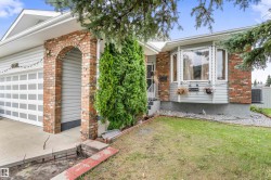 Front exterior featuring brick and siding finishes, a bay window, an arched brick entryway, an attached garage, and mature landscaping - 
