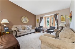 Living area featuring a vaulted ceiling, neutral carpet flooring, and a bay window - 