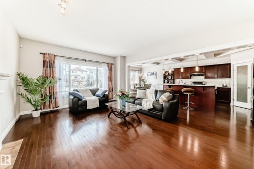 Open-concept living space featuring wood-finish flooring, a large window, a kitchen island with pendant lighting, dark wood cabinetry, and a white tile backsplash - 1330 114B Street, Edmonton, AB - Indoor Photo Showing Living Room