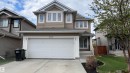 Two-story residence featuring light brown and dark brown siding, an attached two-car garage, multiple upper-level windows, a front entry with steps, and a landscaped front yard with a tree - 1330 114B Street, Edmonton, AB  - Outdoor With Facade 