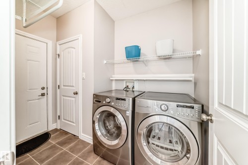 Dedicated laundry area featuring a washer and dryer, tile flooring, and integrated wall shelving - 1330 114B Street, Edmonton, AB - Indoor Photo Showing Laundry Room