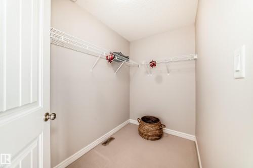 Walk-in closet featuring white wire shelving, light beige wall paint, white baseboards, and neutral carpet flooring - 1330 114B Street, Edmonton, AB - Indoor With Storage