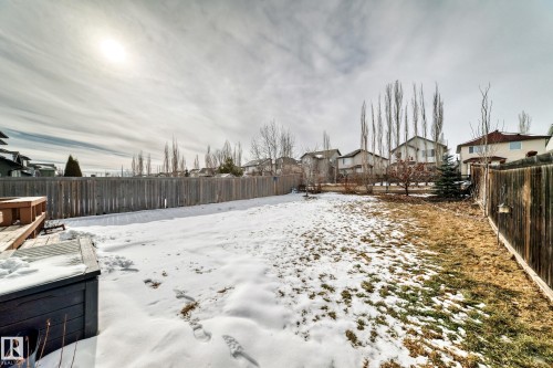 Expansive backyard featuring a partial wood fence, visible decking, and established trees - 1330 114B Street, Edmonton, AB - Outdoor