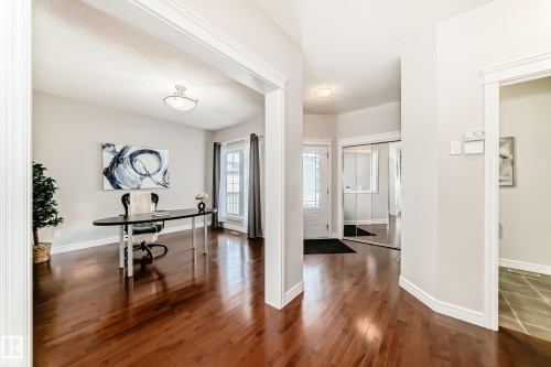 Warm wood-finish flooring extends through the main entry and into an expansive open room - 1330 114B Street, Edmonton, AB - Indoor Photo Showing Other Room