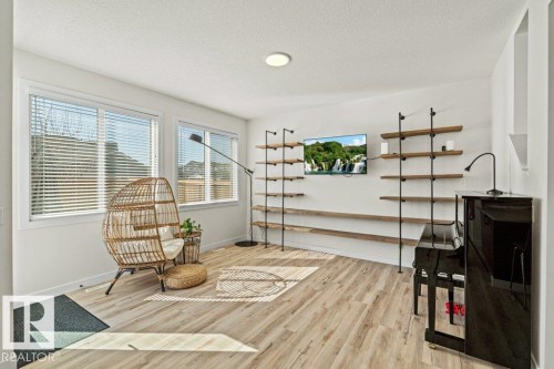 Bright interior space featuring wood-finish flooring and multiple windows with blinds - 21003 131 Avenue, Edmonton, AB 